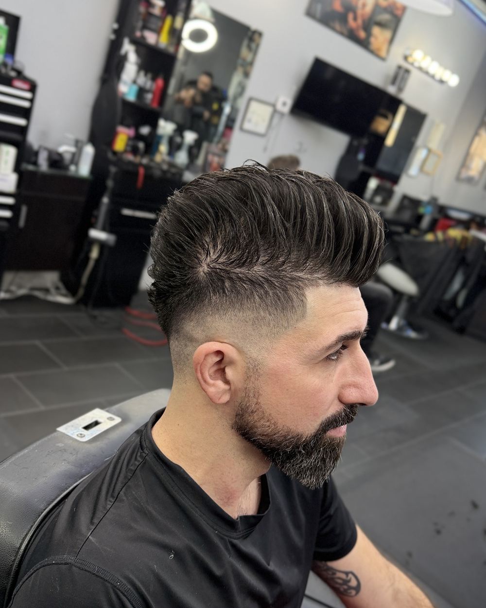 Textured pompadour with a mid skin fade and a lined-up beard